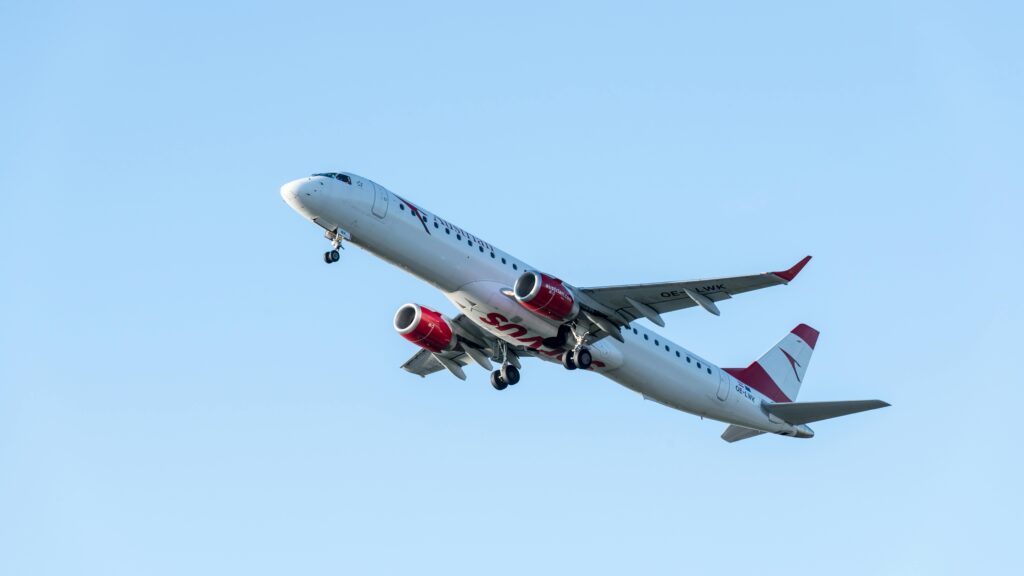 An Austrian Airlines jet airliner ascending into a clear blue sky, captured mid-flight.